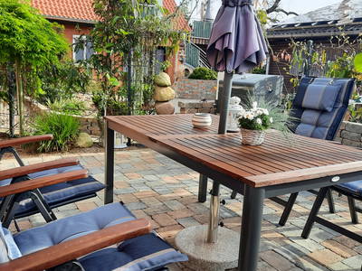 Überdachte Terrasse mit bequemer Garnitur , Sonnenschirm und Grill.