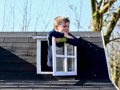 Kind guckt aus Fenster vom Kinder-Spielhaus