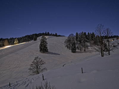 Blick vom Balkon bei Nacht auf den Skihang gegenüber