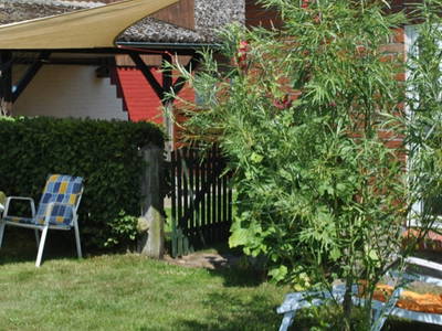 Der Sitzplatz im Garten, hinter der Hecke ist eine überdachte Terasse