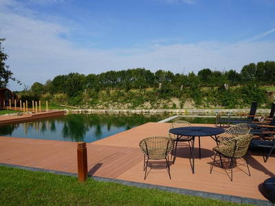 Schwimmteich mit Sonnenliegen und Sitzmöbeln