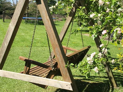 Schaukelbank zwischen Apfel- und Pflaumenbaum; im Hintergrund das große Trampolin.