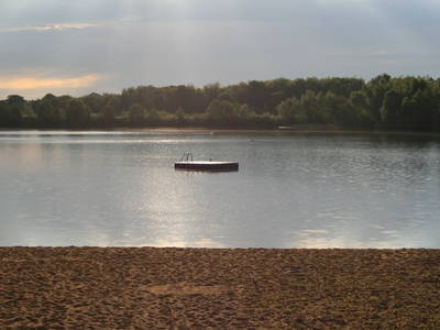 Ein Blick auf den Badesee mit Insel. Davor: einmaliger Sandstrand