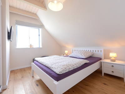 Bild in das Schlafzimmer mit Doppelbett und TV