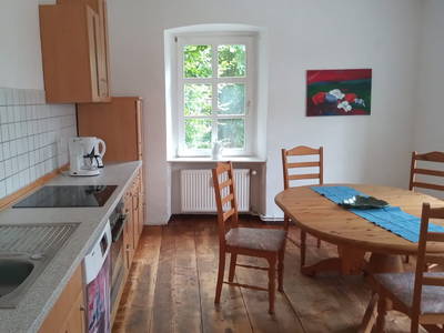 Blick in die Essküche links Kühlschrank, Geschirrspüler, Herd mit Backofen, Spüle - rechts Tisch mit 6 Stühlen